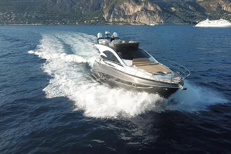  Yacht Photos Pics 2025 Cobrey 52 FLY yacht cruising on open water with scenic coastal backdrop.