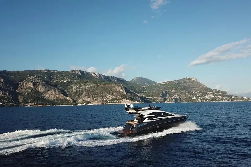  Yacht Photos Pics 2025 Cobrey 52 FLY yacht cruising on scenic coastal waters with mountainous backdrop.