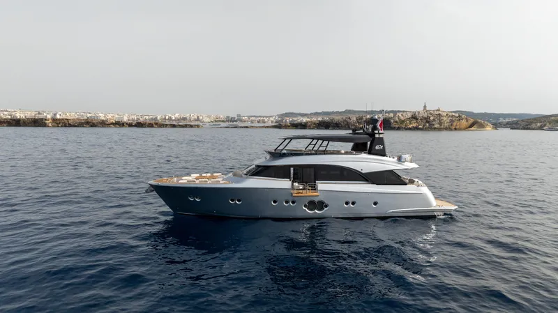 Venus Yacht Photos Pics Luxurious 2013 Monte Carlo Yachts 86'7'' cruising on serene waters near a coastal cityscape.