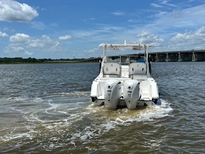  Yacht Photos Pics 2023 Edgewater 280 CX boat cruising on a sunny day near a bridge.