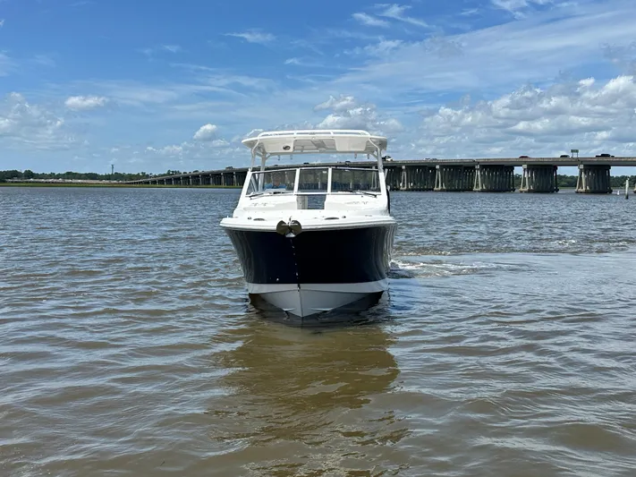  Yacht Photos Pics 2023 Edgewater 280 CX boat on water, with bridge and cloudy sky background.