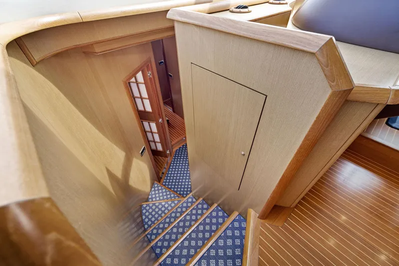 Cetacea Yacht Photos Pics Interior staircase of 2008 Mochi Craft Dolphin yacht with wooden finish and carpeted steps.