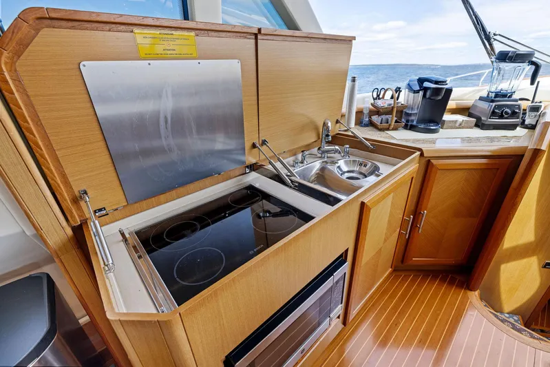 Cetacea Yacht Photos Pics 2008 Mochi Craft Dolphin yacht kitchen with stove, sink, and wooden cabinetry.