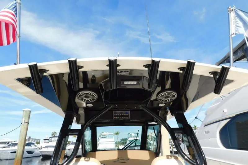  Yacht Photos Pics 2024 Scout 330 LXF boat with rod holders and speakers, docked under a clear sky.