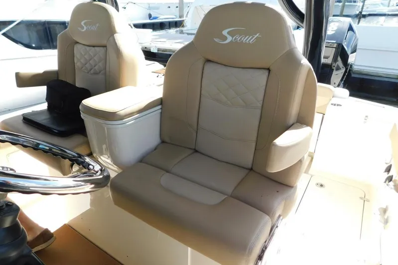  Yacht Photos Pics 2024 Scout 330 LXF boat interior with luxurious beige seating and steering wheel.