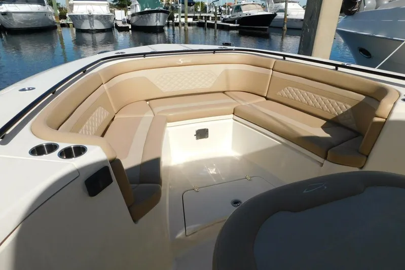  Yacht Photos Pics 2024 Scout 330 LXF boat interior with tan seating and cup holders at a marina.