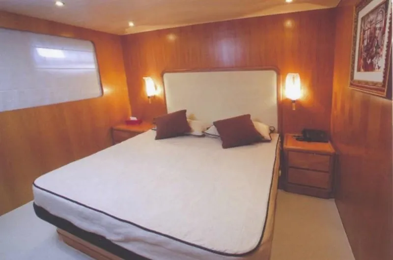  Yacht Photos Pics Luxurious bedroom interior on a 2001 Castagnola 30 mt yacht, featuring wood paneling and cozy lighting.