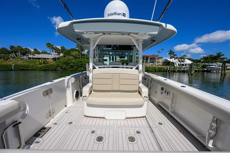 Who's Sippin Yacht Photos Pics 2021 Boston Whaler 380 Outrage boat with spacious deck and seating, docked by lush greenery.