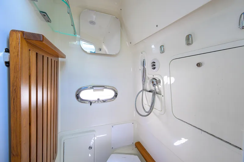 Who's Sippin Yacht Photos Pics 2021 Boston Whaler 380 Outrage bathroom with shower, wooden accents, and porthole window.
