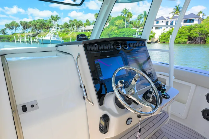 Who's Sippin Yacht Photos Pics 2021 Boston Whaler 380 Outrage helm with modern navigation system and scenic waterfront view.