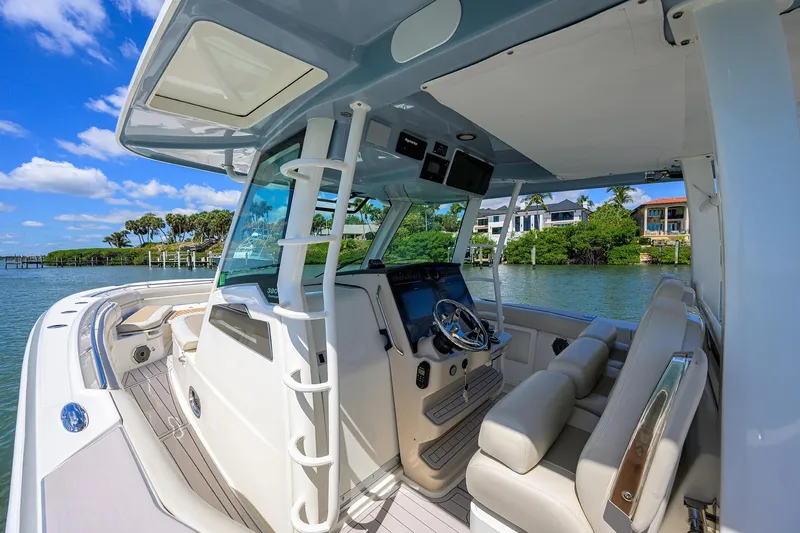 Who's Sippin Yacht Photos Pics 2021 Boston Whaler 380 Outrage boat interior with helm, luxurious seating, and waterfront view.