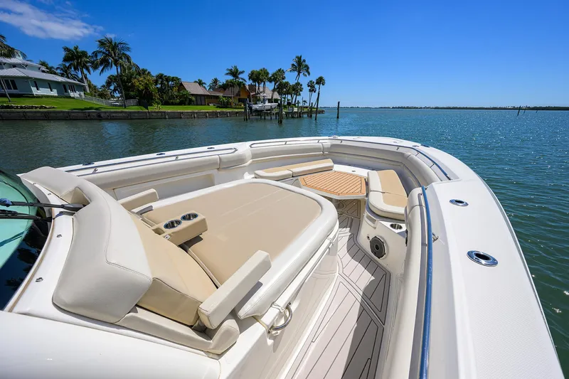 Who's Sippin Yacht Photos Pics 2021 Boston Whaler 380 Outrage boat with luxurious seating, docked by a scenic waterfront.