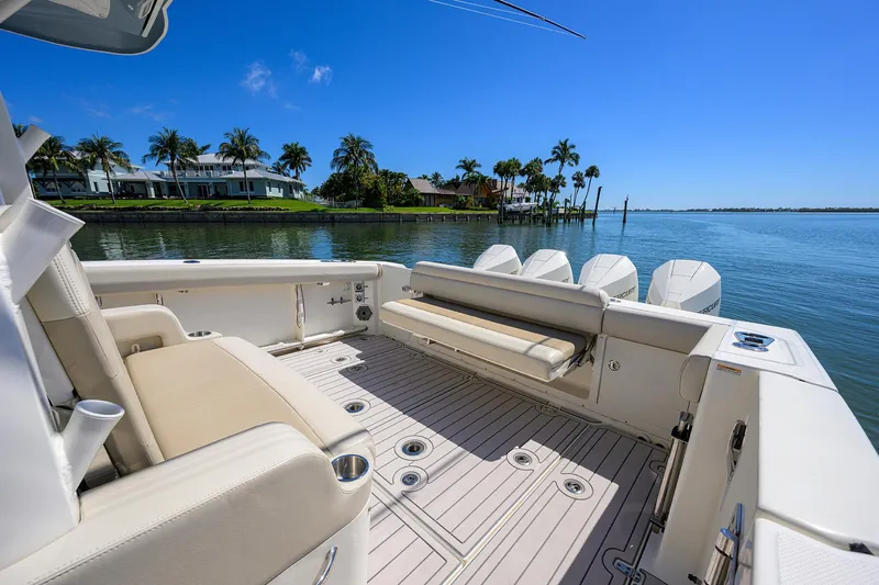 Who's Sippin Yacht Photos Pics Boston Whaler 380 Outrage 2021 boat deck with seating, overlooking serene waterfront and palm trees.