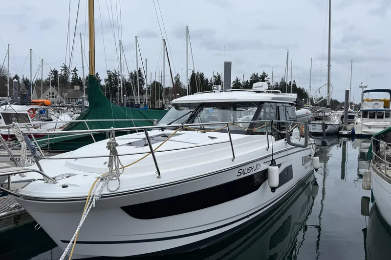  Yacht Photos Pics 2023 Jeanneau NC 1095 boat docked in a marina, surrounded by other vessels.