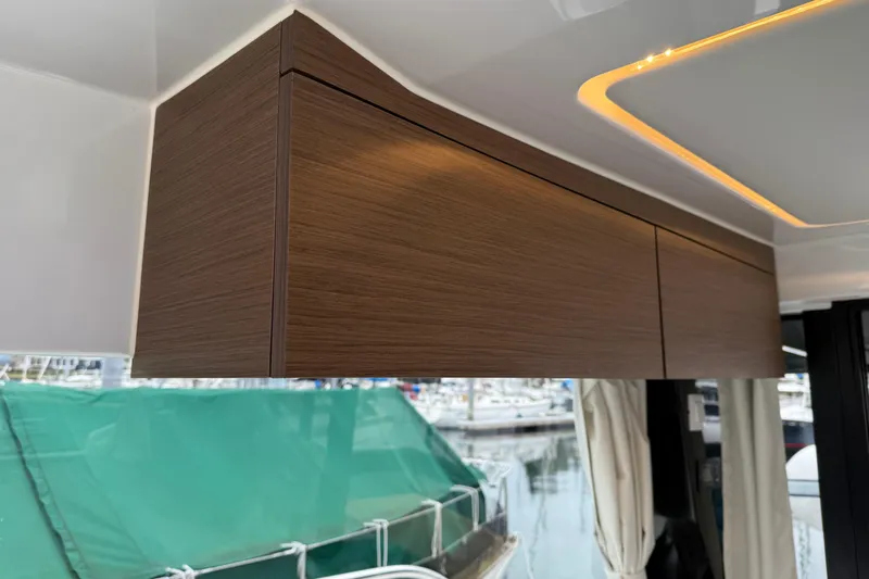  Yacht Photos Pics Interior of 2023 Jeanneau NC 1095 boat with sleek wooden cabinetry and modern lighting.