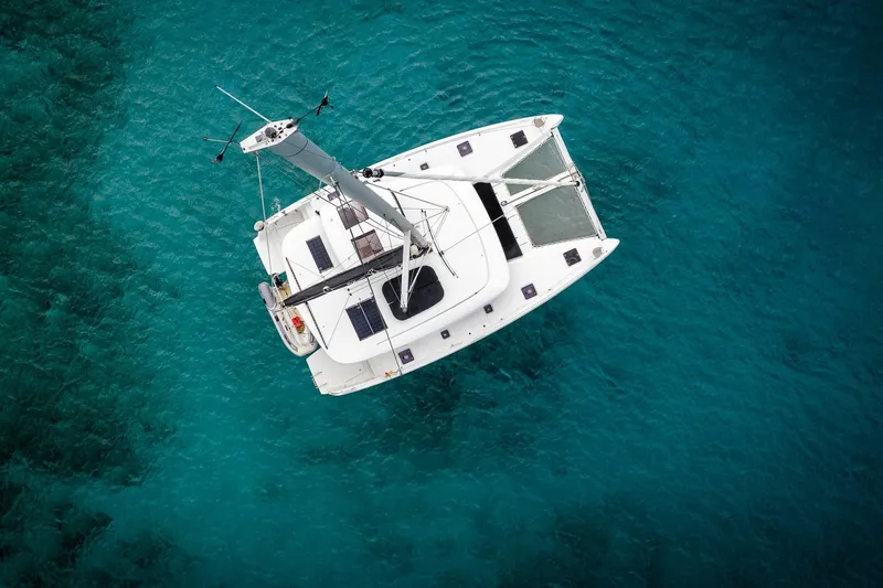 Tide Together Yacht Photos Pics Aerial view of 2023 Lagoon 42 catamaran sailing on clear turquoise water.