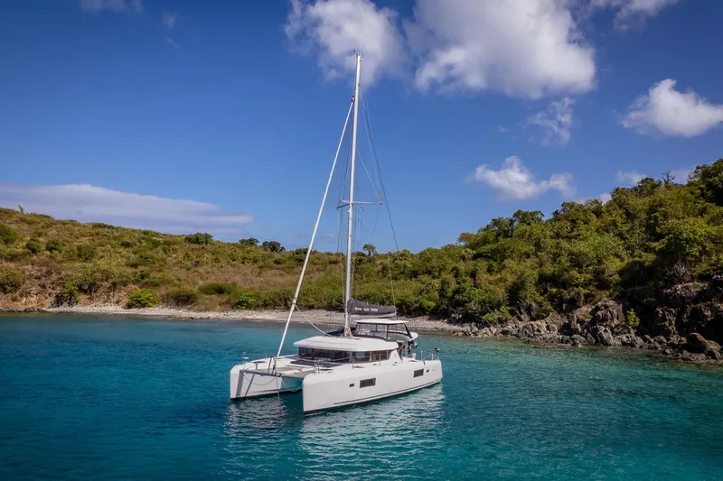 Tide Together Yacht Photos Pics 2023 Lagoon 42 catamaran anchored in a serene, tropical bay with clear blue water.