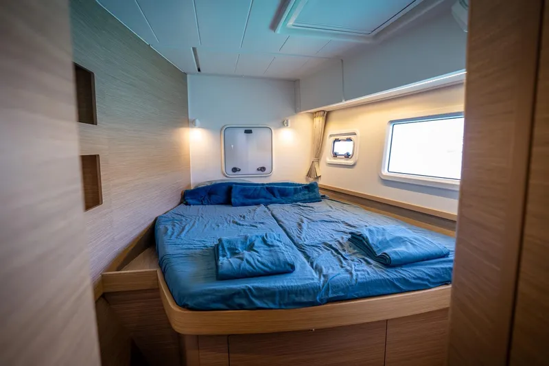Tide Together Yacht Photos Pics Luxurious cabin interior of 2023 Lagoon 42 catamaran with cozy bedding and modern design.