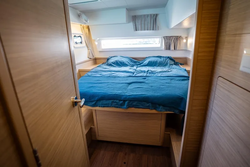 Tide Together Yacht Photos Pics 2023 Lagoon 42 yacht cabin with cozy bed and wooden interior.