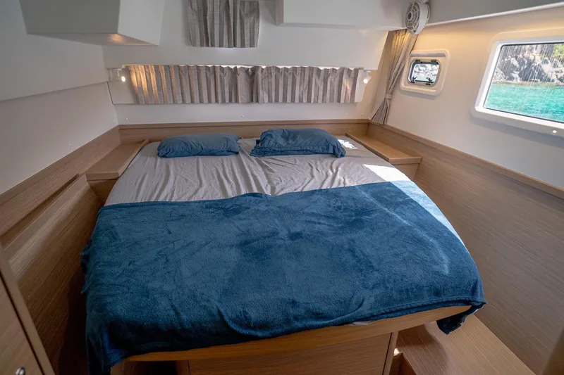 Tide Together Yacht Photos Pics Luxurious cabin interior of 2023 Lagoon 42 catamaran with cozy bedding and natural light.
