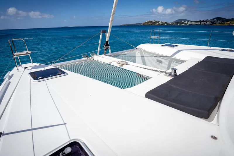 Tide Together Yacht Photos Pics 2023 Lagoon 42 catamaran deck with netting, overlooking clear blue ocean and distant islands.