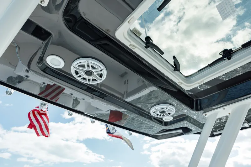 Mindy's Tyde III Yacht Photos Pics 2022 Pursuit S 328 boat roof with speakers and flags against a cloudy sky.