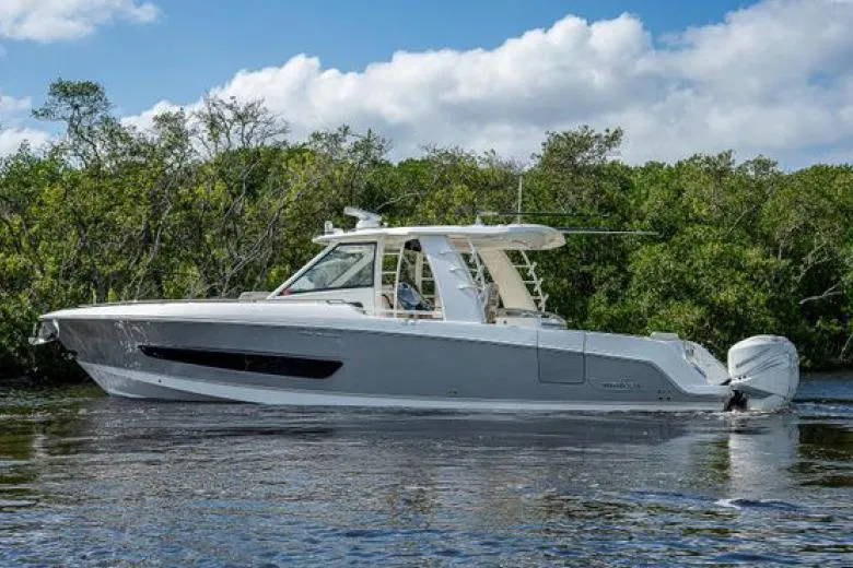 Aj Yacht Photos Pics 2020 Boston Whaler 420 Outrage boat on calm water, surrounded by lush greenery.