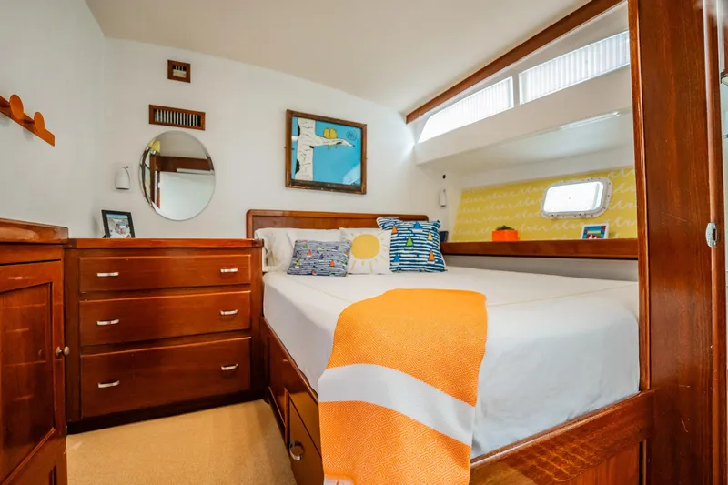 Miss Phebe II Yacht Photos Pics Cozy bedroom interior of 1971 Whiticar 62 Convertible yacht with wooden furniture and colorful decor.