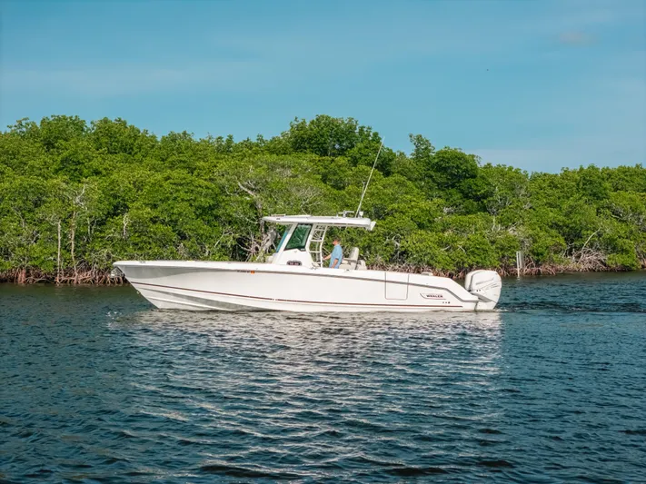 Rock N’ Doc Yacht Photos Pics 2019 Boston Whaler 330 Outrage boat cruising on a calm river with lush green trees.