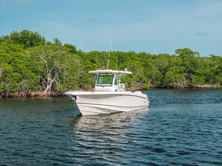 Rock N’ Doc Yacht Photos Pics 2019 Boston Whaler 330 Outrage boat cruising on a calm river with lush green trees.