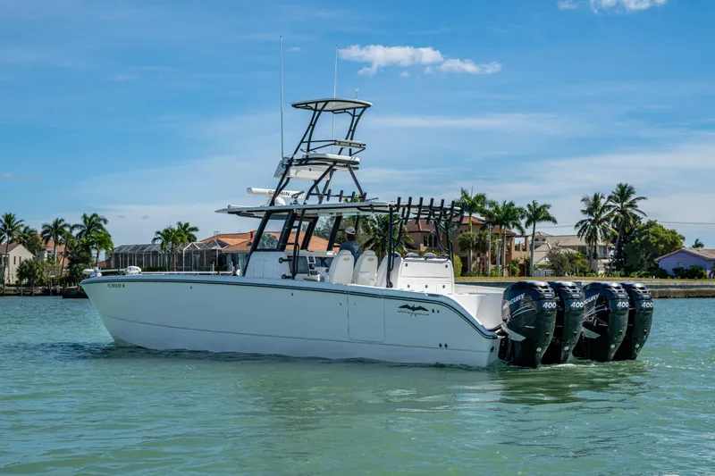Hoosier Hooker Yacht Photos Pics 2021 Invincible 40 Catamaran with four outboard engines on calm water, palm trees in background.