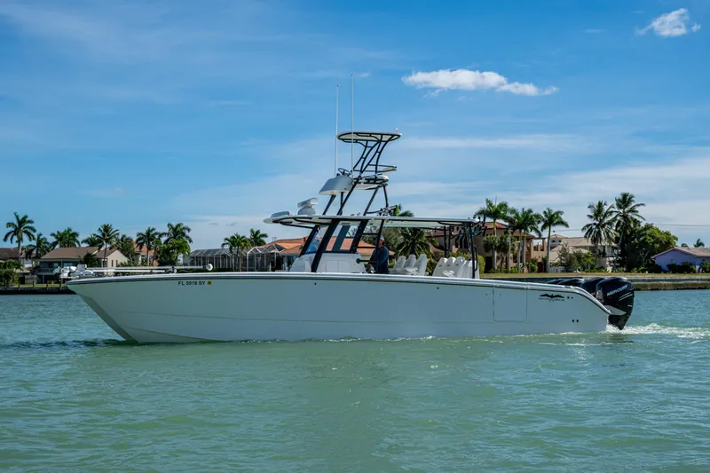 Hoosier Hooker Yacht Photos Pics 2021 Invincible 40 Catamaran cruising on a sunny day near palm-lined shore.