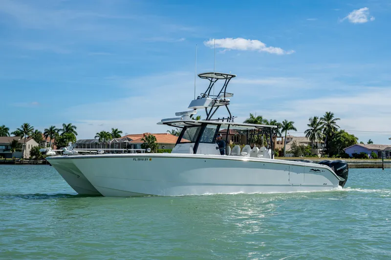 Hoosier Hooker Yacht Photos Pics 2021 Invincible 40 Catamaran cruising on a sunny day near waterfront homes.