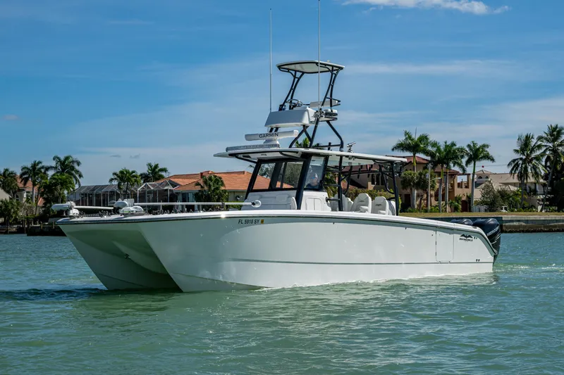Hoosier Hooker Yacht Photos Pics 2021 Invincible 40 Catamaran cruising on a sunny day near waterfront homes.