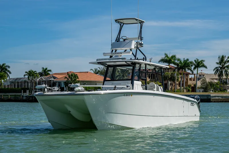 Hoosier Hooker Yacht Photos Pics 2021 Invincible 40 Catamaran cruising on a sunny day near waterfront homes.
