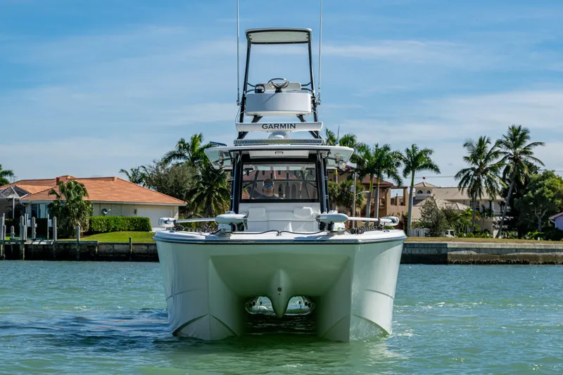 Hoosier Hooker Yacht Photos Pics 2021 Invincible 40 Catamaran on water, with tropical backdrop and clear sky.
