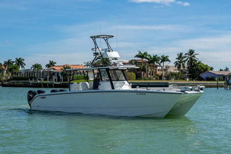 Hoosier Hooker Yacht Photos Pics 2021 Invincible 40 Catamaran cruising on a sunny day near waterfront homes.