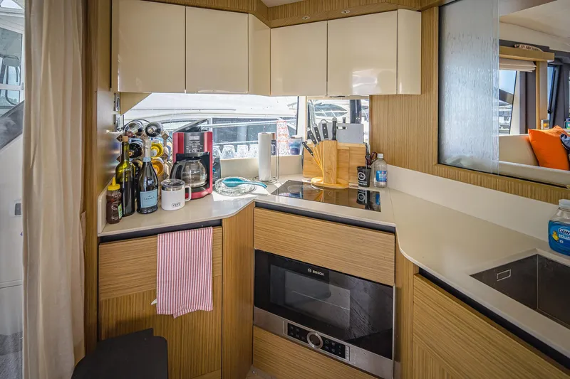 Tara Yacht Photos Pics Modern kitchen interior on 2017 Absolute 50 Fly yacht with appliances and wooden cabinetry.