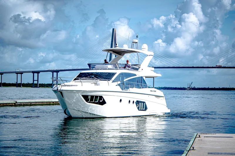 Tara Yacht Photos Pics Luxurious 2017 Absolute 50 Fly yacht cruising near a bridge under a cloudy sky.