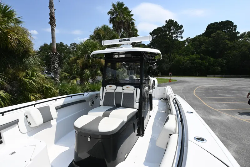  Yacht Photos Pics 2020 Tidewater 320 CC Adventure boat with sleek design, parked near lush greenery.