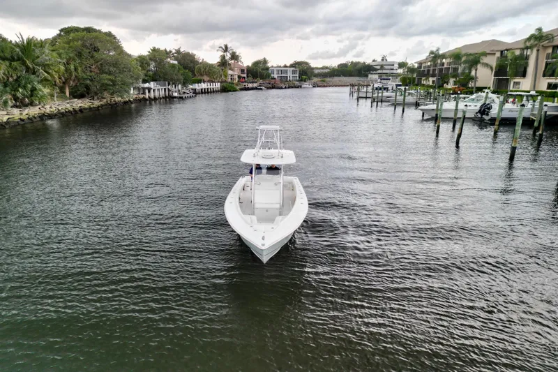 Ribeye Yacht Photos Pics 2005 Jupiter 31 Center Console boat on a calm waterway, surrounded by lush greenery and docks.