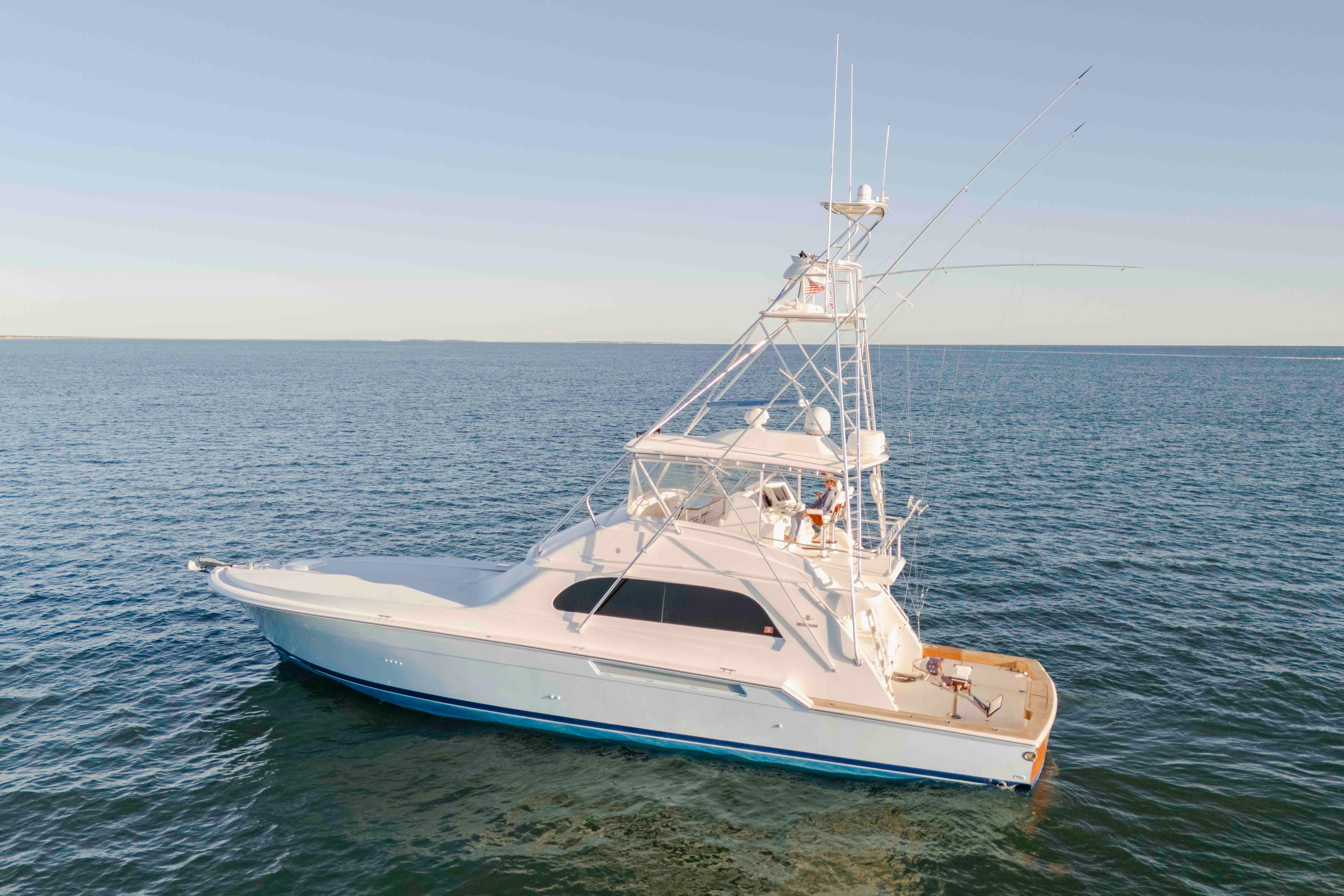 1999 Bertram 60 Convertible yacht cruising on open sea under clear sky.