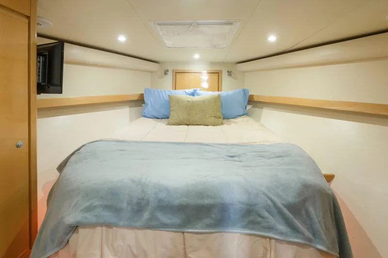 Lady Dianne Yacht Photos Pics Cozy bedroom interior of 1999 Bertram 60 Convertible yacht with soft lighting and plush bedding.