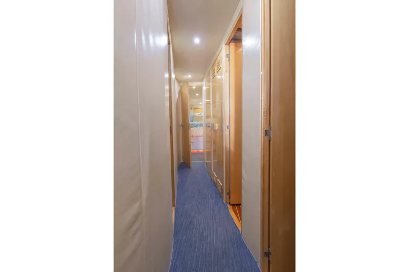 Lady Dianne Yacht Photos Pics Interior hallway of a 1999 Bertram 60 Convertible yacht with wooden doors and blue carpet.