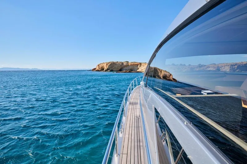 Nickel Yacht Photos Pics 2008 Pershing 64 yacht cruising near rocky coastline under clear blue sky.
