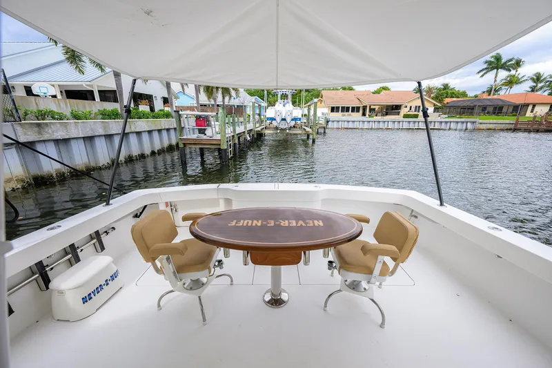  Yacht Photos Pics 2008 Viking 56 Enclosed Bridge yacht deck with chairs and table, overlooking a serene waterfront.