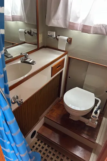 Brie Yacht Photos Pics 1980 Grand Banks 36 Classic yacht bathroom with sink, toilet, and blue shower curtain.