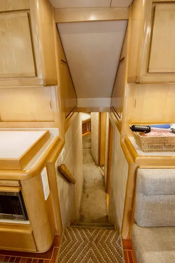 Tres Juanes Yacht Photos Pics Interior of 1997 Bertram 54 Convertible yacht, featuring wooden cabinetry and carpeted stairs.