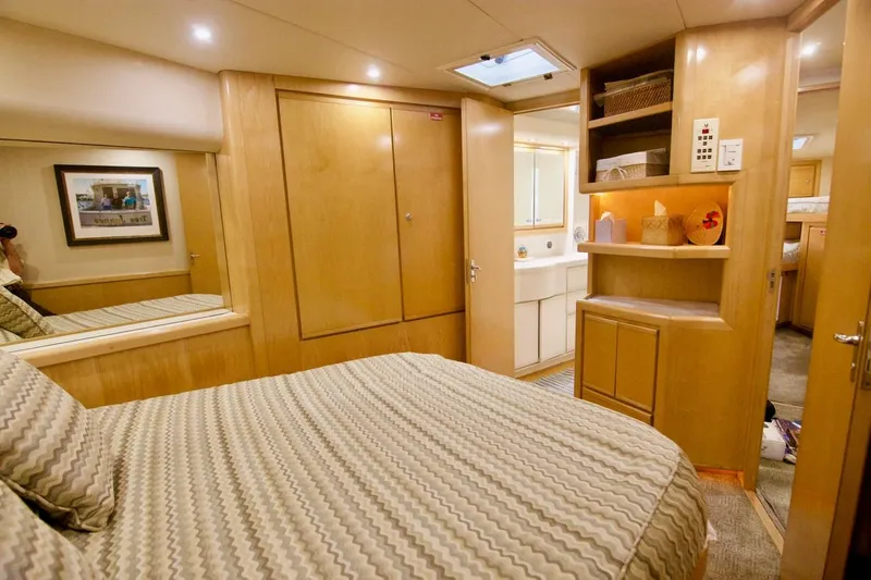 Tres Juanes Yacht Photos Pics Luxurious bedroom interior of a 1997 Bertram 54 Convertible yacht with wood finishes.