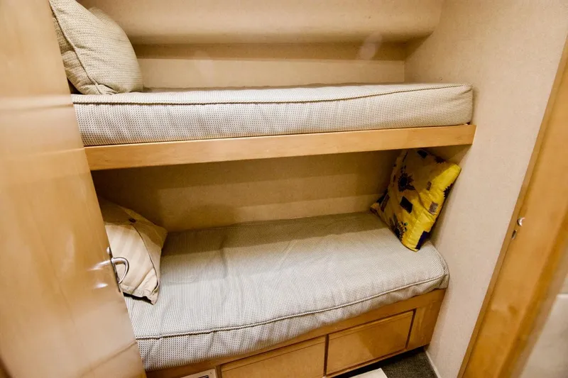 Tres Juanes Yacht Photos Pics Bunk beds in a 1997 Bertram 54 Convertible yacht cabin, featuring cozy bedding and pillows.